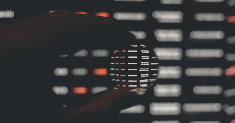 Hand with magnitude glass over monitor with data table