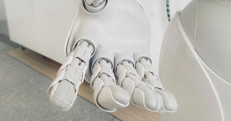 A robotic hand of a white robot reaching out
