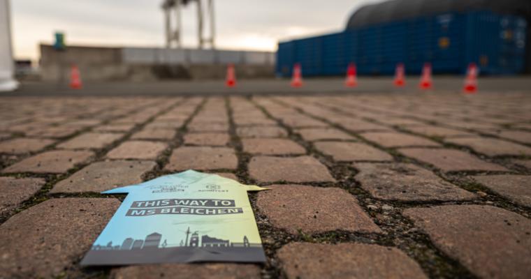 Directional sign on cobblestones reading \"This Way to MS Bleichen\" with the ContainerDays Hamburg 2026 logo, guiding attendees to the venue at the harbor